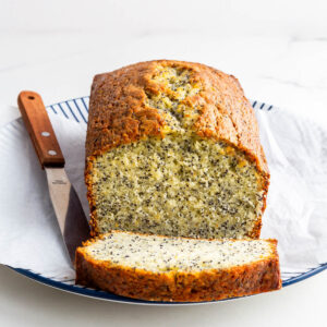 Slicing an orange cake with poppy seeds to serve it.