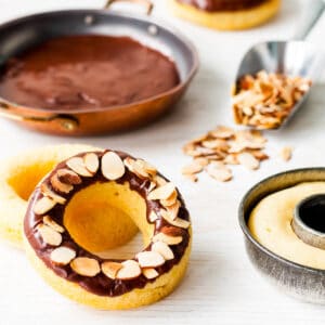 Baked donuts dipped in chocolate icing and topped with sliced almonds.