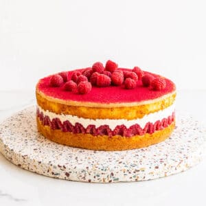 Raspberry layer cake on a terrazzo board.