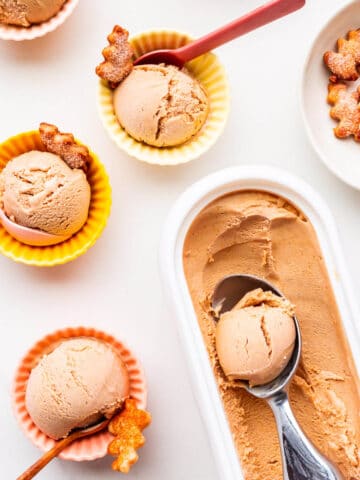 Scoops of pumpkin ice cream in little bowls with pie crust cookies.