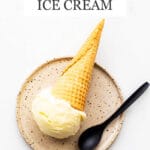 Lemon custard ice cream in a cone served on a ceramic plate with a black spoon