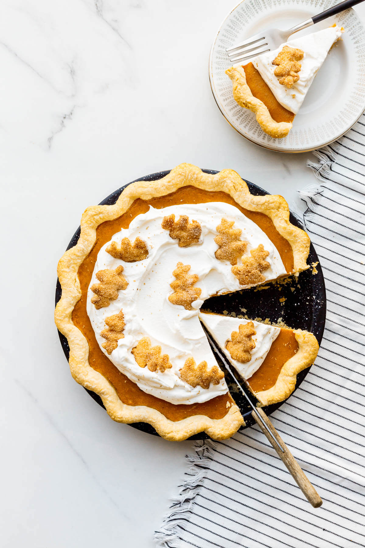 Slicing and serving a whipped cream topped sweet potato pie.