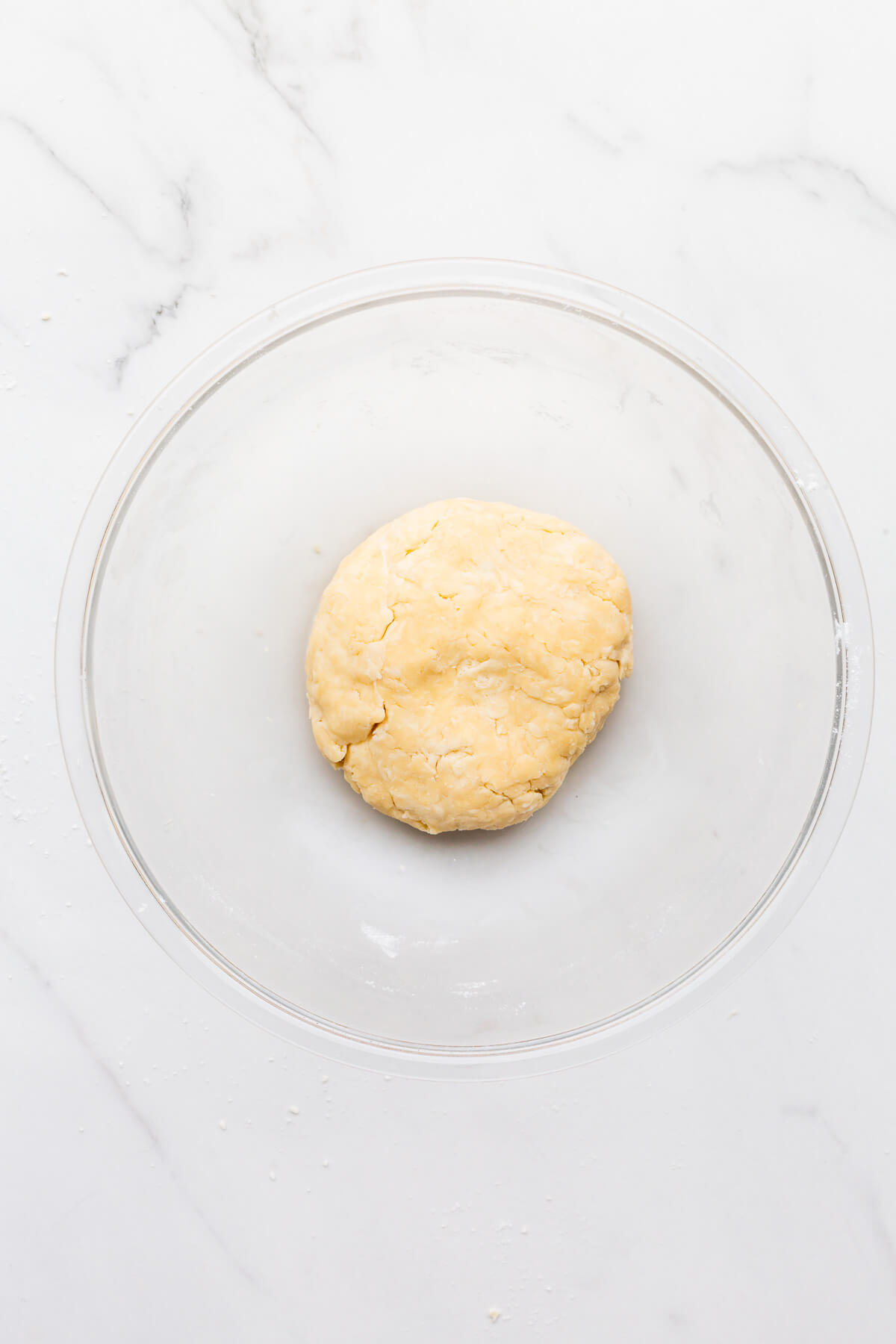 A disk of homemade pie crust in a bowl.