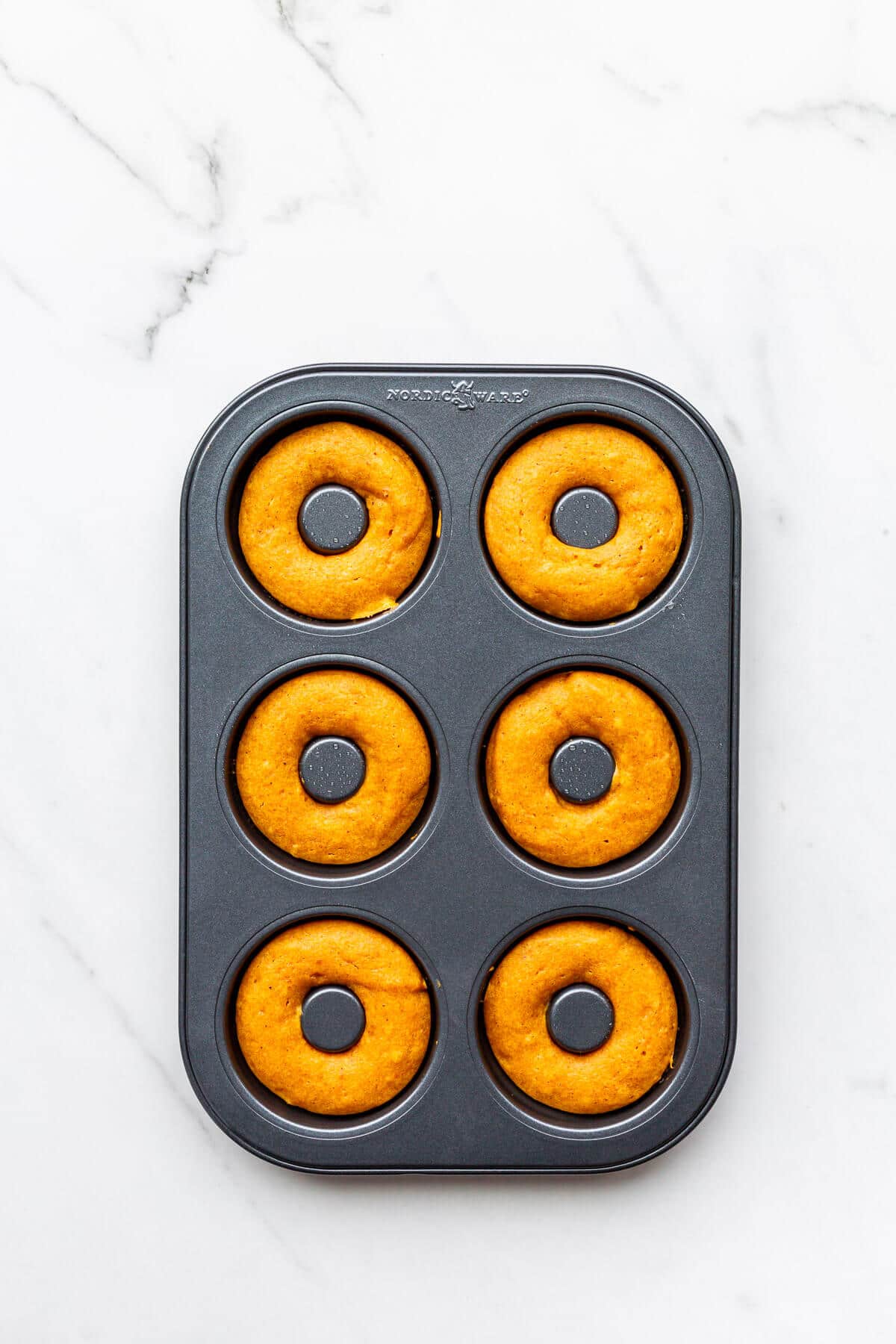 Pumpkin donuts in a donut pan after baking.