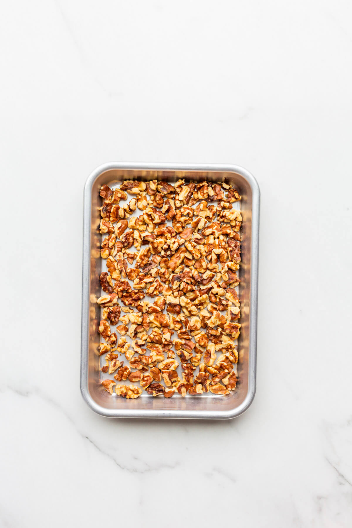 Walnuts toasted on a mini sheet pan.