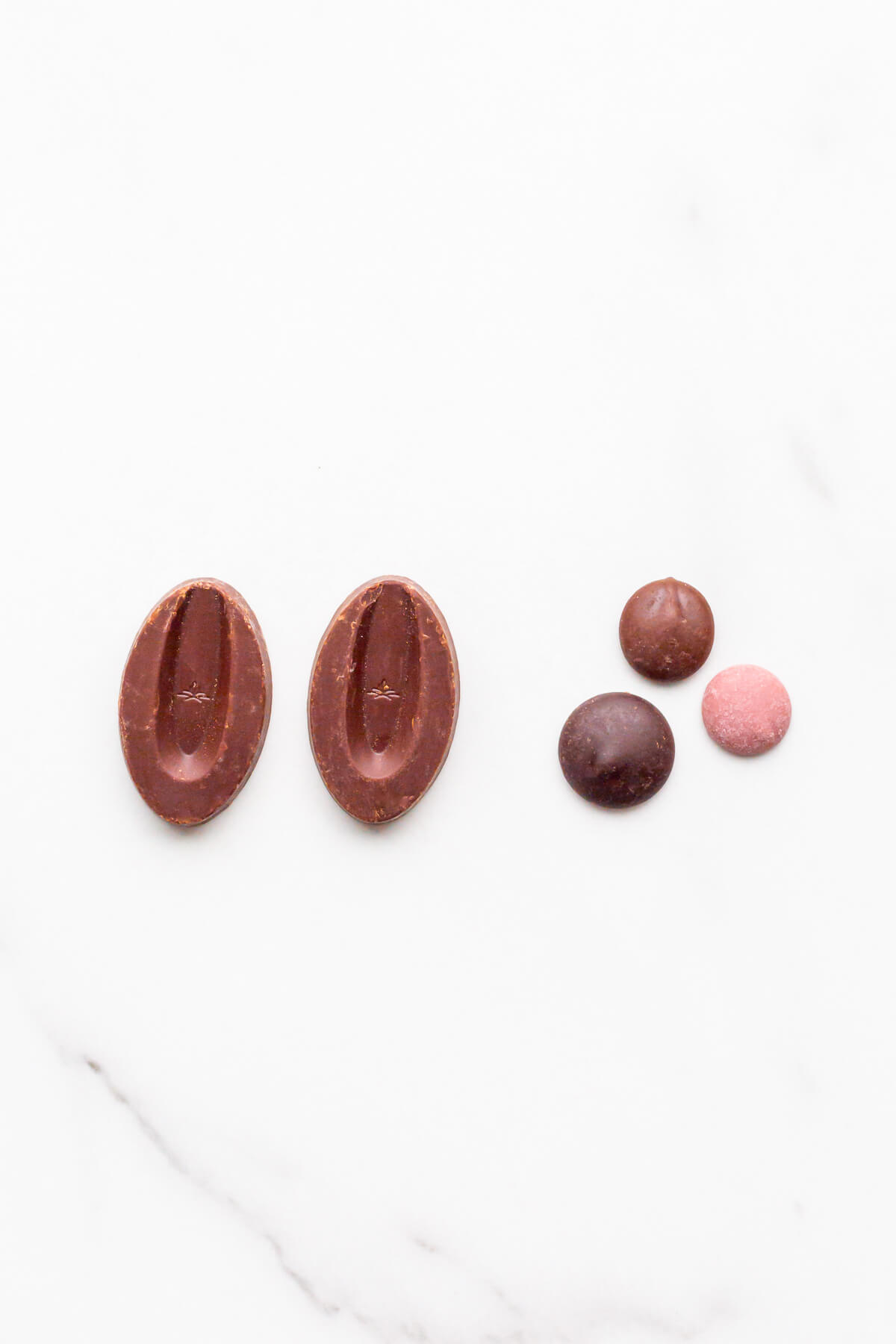 Different shapes chocolate pieces for bakers are sold in: a bean-shaped oval chocolate from Valrhona and chocolate buttons (also called pistols) from Cacao Barry.